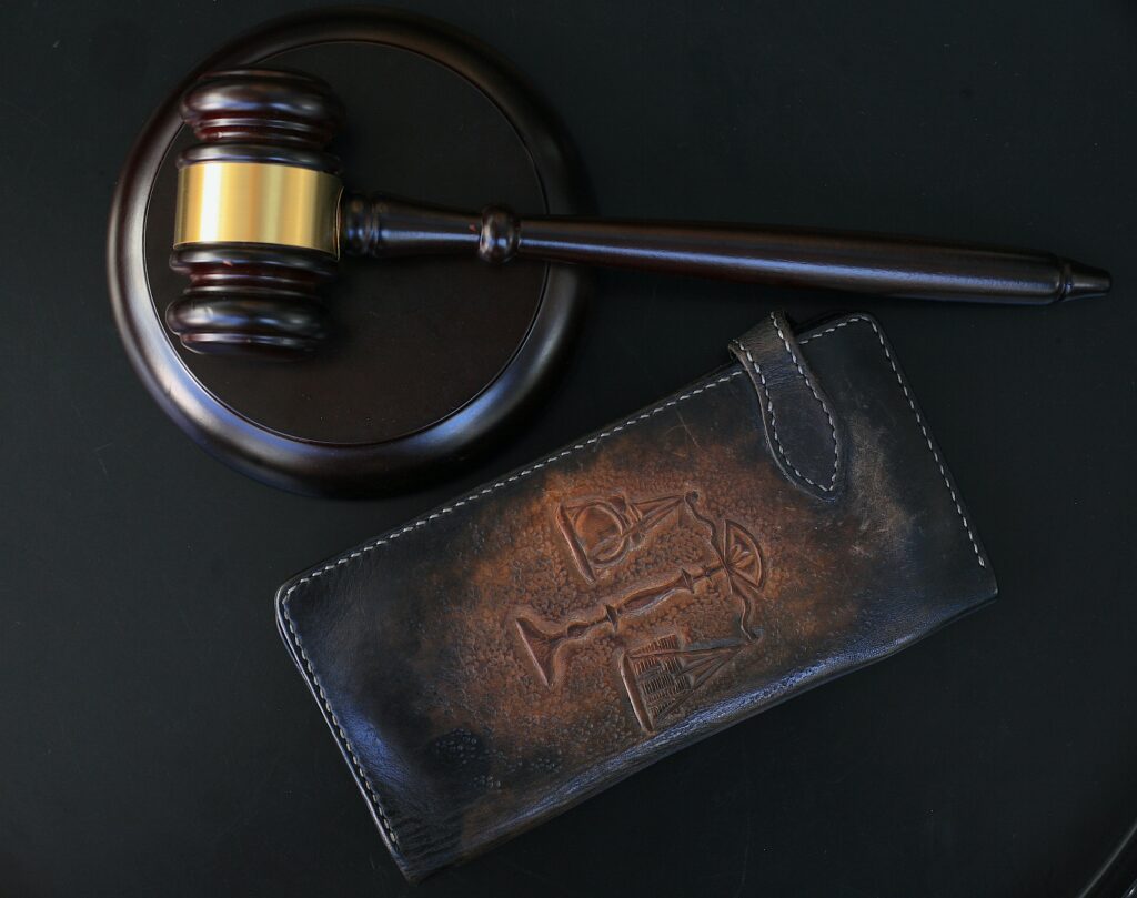 A dark wooden judge's gavel resting on a matching sounding block against a dim, dramatic background, representing the legal system.