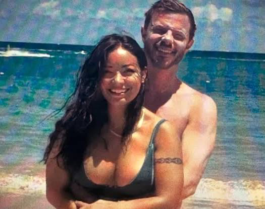 Mica Miller and her estranged husband John-Paul Miller posing together on a sunny beach with the ocean in the background.