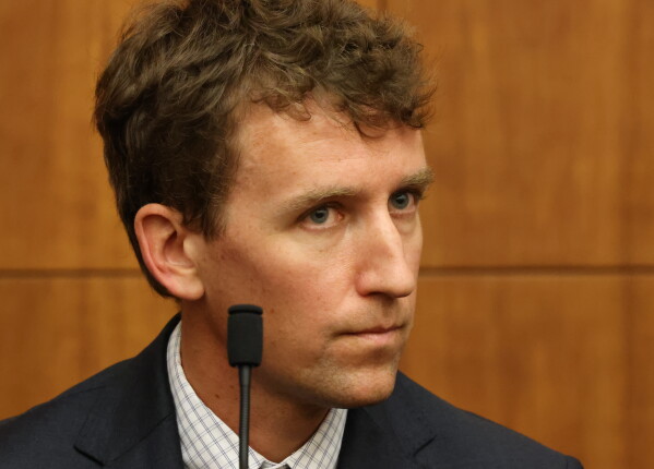 courtroom picture of Patrick Clancy on the stand in a suit and tie