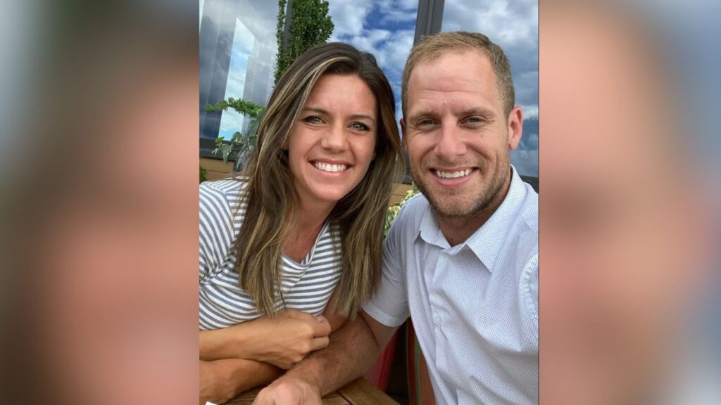 A happy personal photograph of Caleb Flynn smiling alongside his wife, Ashley Flynn, outdoors.