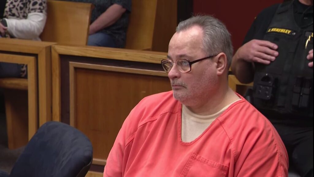 A close-up photograph of John Skelton looking ahead with a serious expression inside a Michigan courtroom
