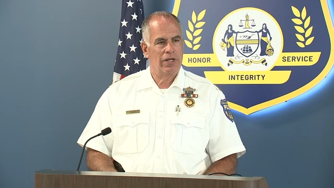 A Philadelphia law enforcement official speaking at a press conference podium with microphones, providing updates to reporters on a high-profile criminal investigation.